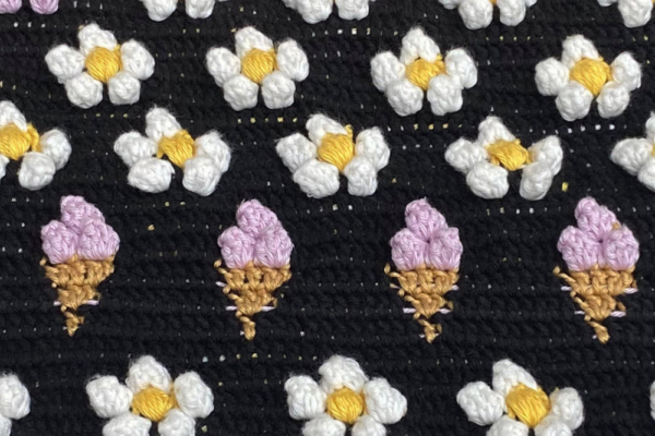 details of crocheted laptop sleeve with strawbery flowers and icecream pattern