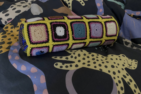 mini bolster cover made of tiny colored granny suares on animal bedding