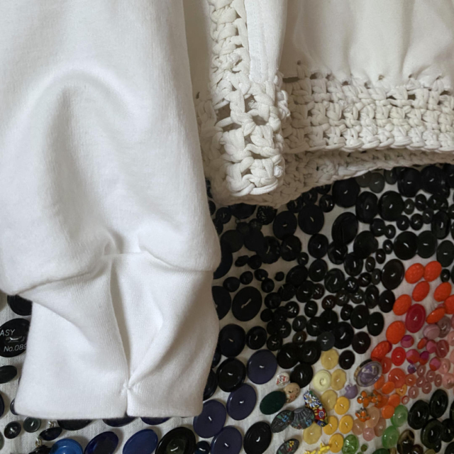 sleeve cuffs of white jumper in front of colorful buttonrepository