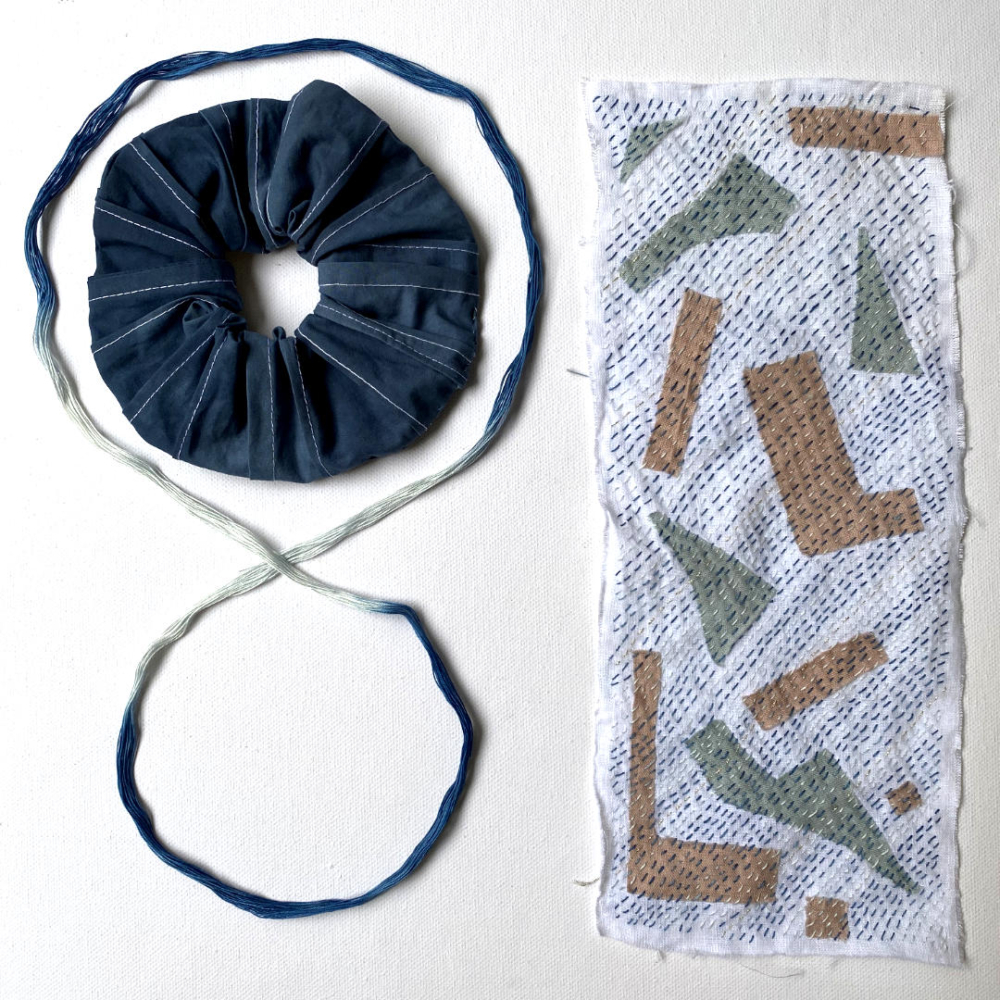 white linen with found shapes and indigo yarn running stitches