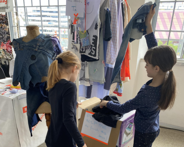 2 girls pulling old jeans out of a box
