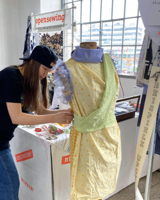 girl putting together yellow, light green and light blue dress on mannequin