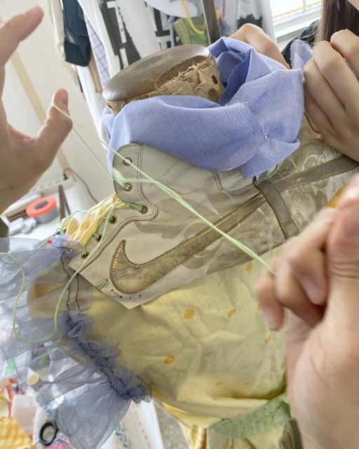 hands stitching sneaker part on dress