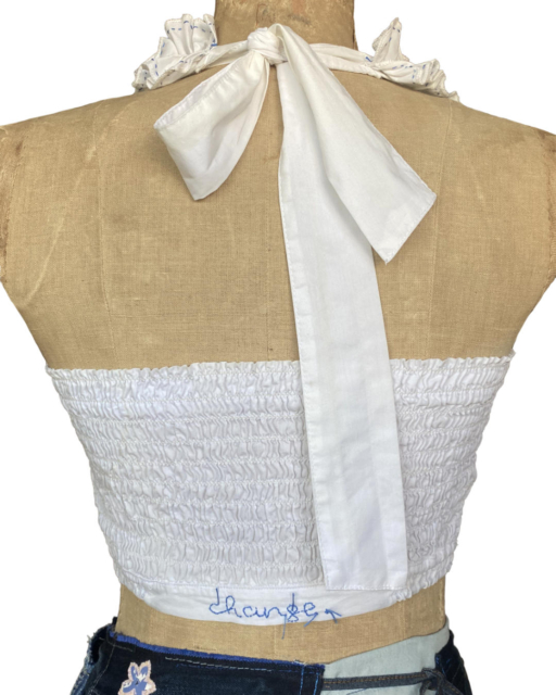 backside of white top with neck bow and embroidered change